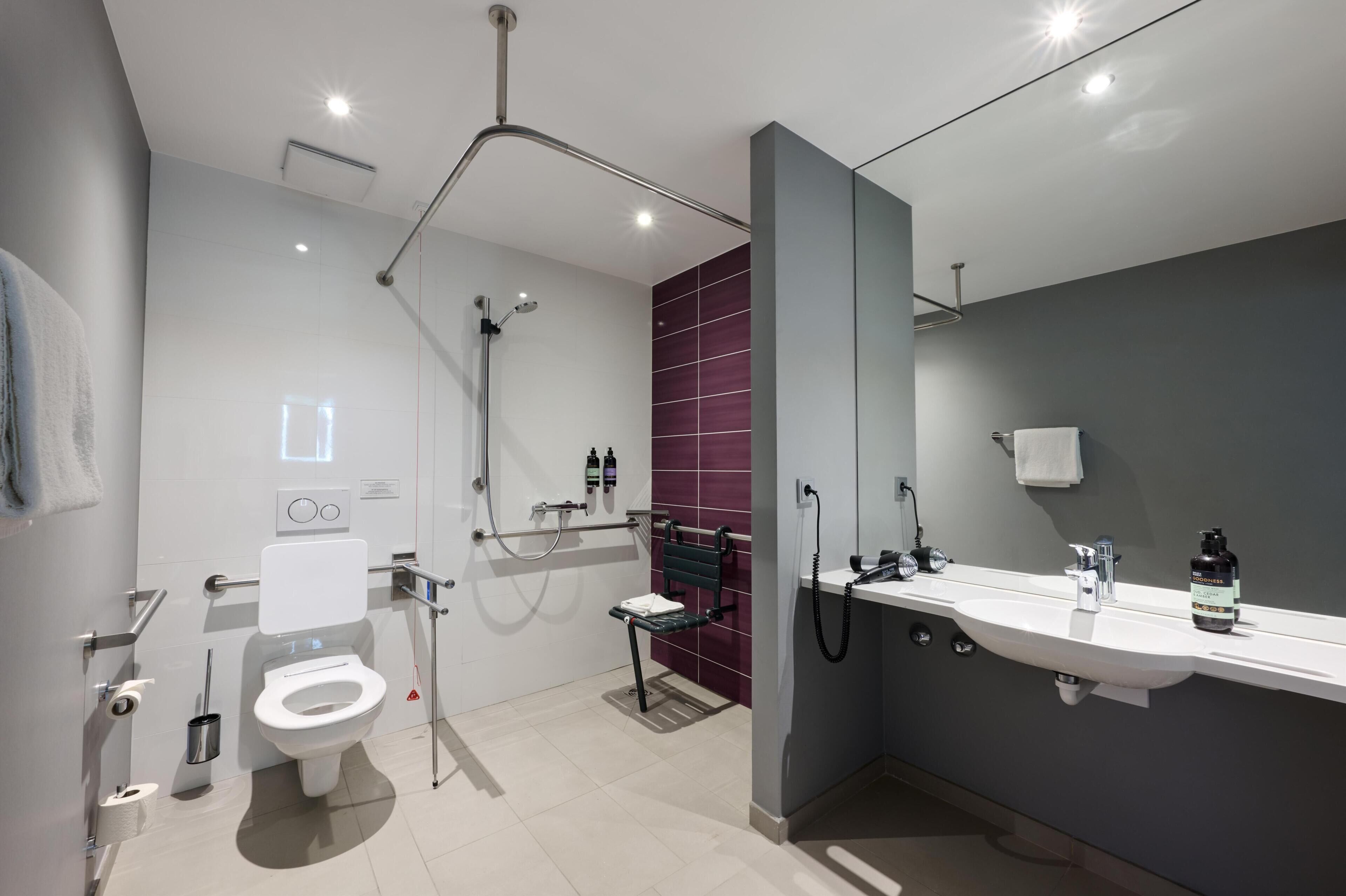 A modern bathroom with a toilet, shower, and sink.