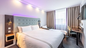 Una habitación de hotel con una cama grande, mesitas de noche, un escritorio y una silla.
