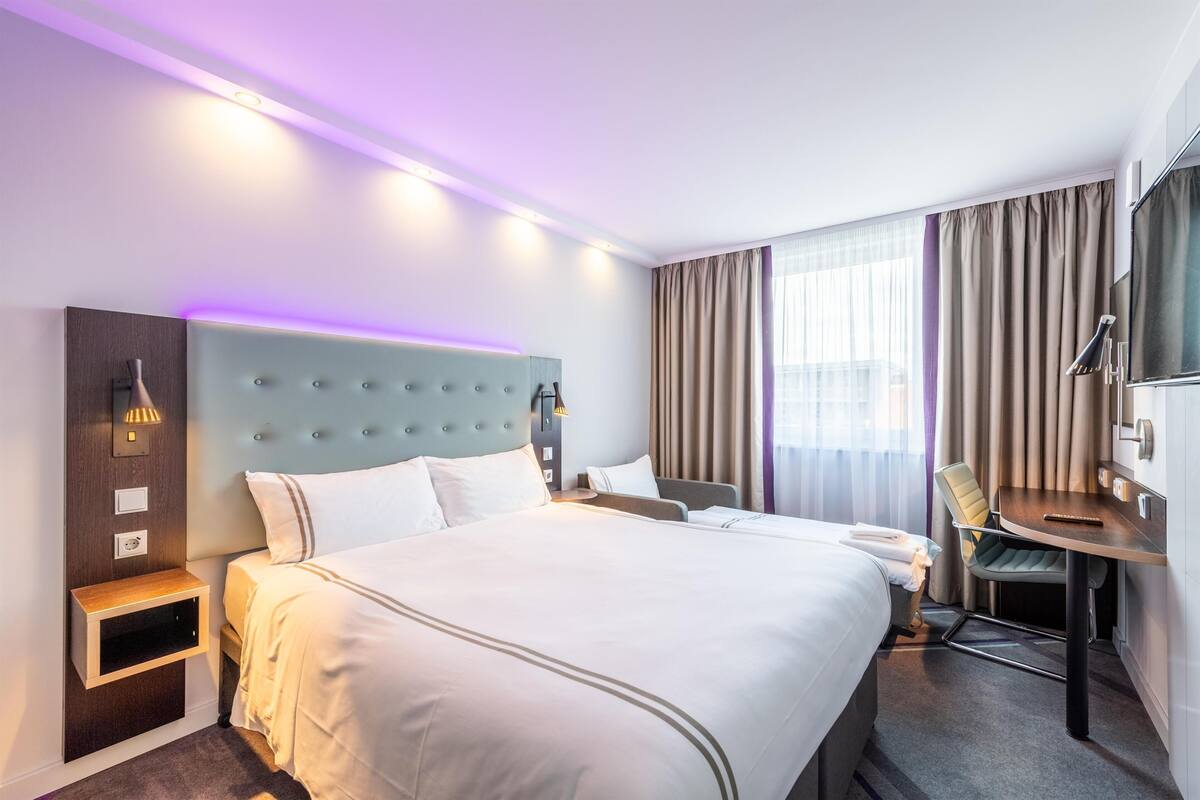 A hotel room with a large bed, bedside tables, a desk, and a chair.