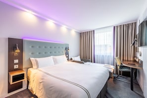 Een hotelkamer met een groot bed, nachtkastjes, een bureau en een stoel.