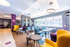 Een moderne hotel lobby met zitgedeeltes, een receptiebalie en grote ramen met uitzicht.