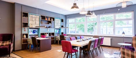 A modern interior with a dining area, bookshelves, and large windows.