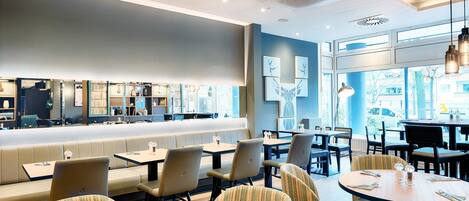 A restaurant with a long counter, booths, and tables.