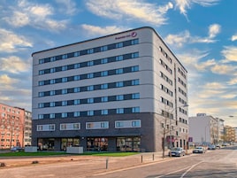 Un hotel moderno con fachada plana, múltiples ventanas y una entrada visible con puerta de cristal.