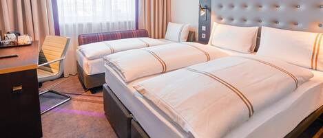 Habitación de hotel con una cama grande, un escritorio, una silla y una ventana con cortinas.