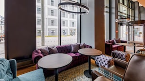 Un intérieur moderne avec un canapé violet, des tables rondes et un tapis à motifs.