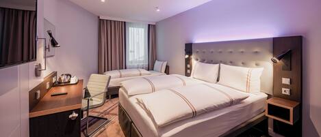 Habitación de hotel con una cama grande, un escritorio con silla, una mesita y un espejo.