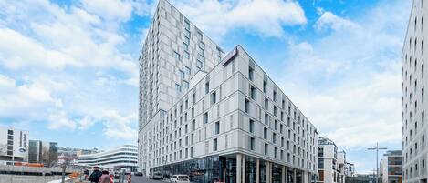 A modern hotel with a prominent corner building, large glass windows, and a clear sky.