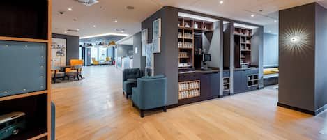 A modern interior with a wooden floor, seating area, and a coffee station with mugs.