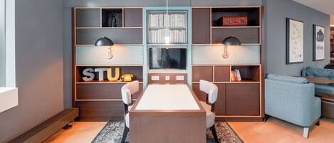 A modern living room with a central table, two chairs, a bookshelf, and a sofa.