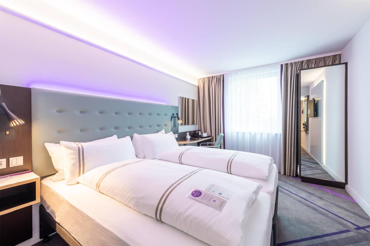 A hotel room with a large bed, bedside tables, a desk, and a mirror.