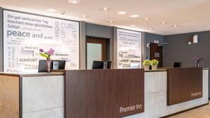 A hotel reception desk with a large sign displaying words like 'peace,' 'quiet,' and 'sleep.' - Premier Inn München Airport Ost (Oberding)