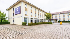 A hotel with a prominent Premier Inn sign, a paved courtyard, and a building with multiple windows. - Premier Inn München Airport Ost (Oberding)