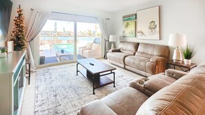 Ein Wohnzimmer mit Sofa, Couchtisch und Blick auf einen Pool und Gebäude.