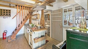 Cuina amb escala de fusta, un rentaplat i una finestra que dona a una vista.