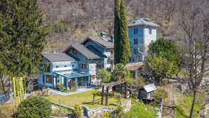 Una casa de diversos pisos amb un hivernacle de vidre, una torre de pedra i un jardí ben cuidat.