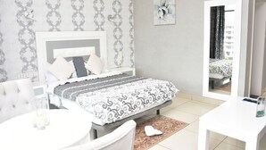 A bedroom with a bed, bedside table, and a mirror. - Hotel Carmen Galaxi (Malabo)