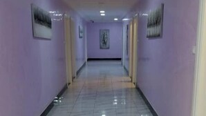 A hallway with purple walls and a shiny tiled floor. - Hotel Carmen Galaxi (Malabo)