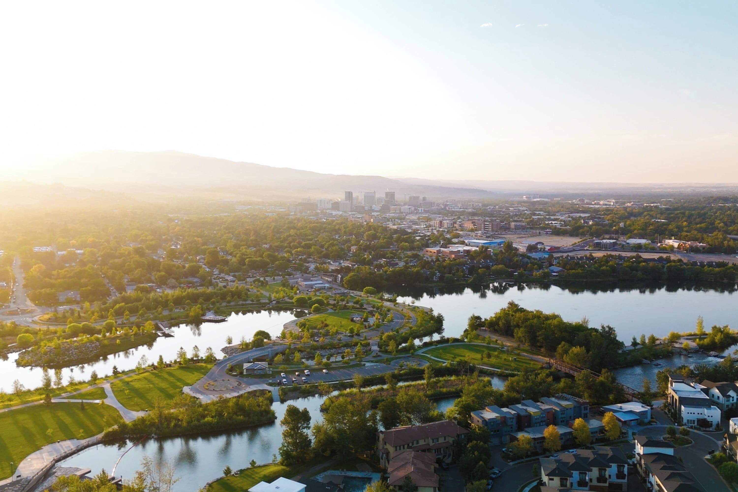 Vista aérea de una zona residencial con un lago, rodeada de vegetación y edificios.