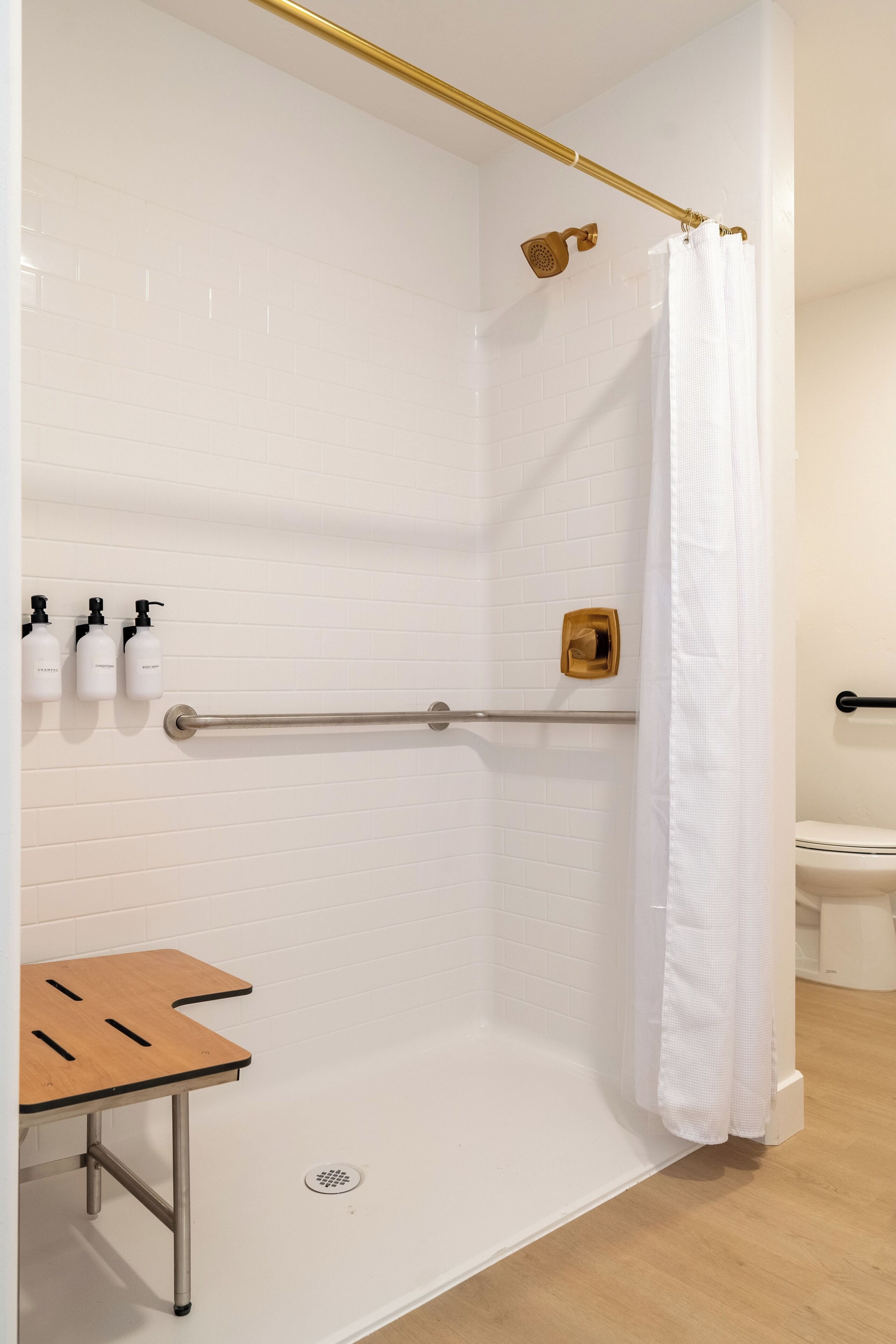 A modern bathroom with a shower, a toilet, and a small wooden table.