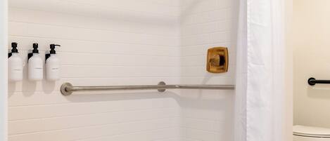 A modern bathroom with a shower, a toilet, and a small wooden table.
