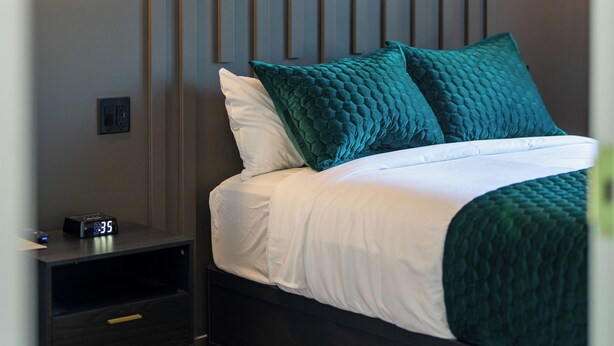 Een moderne slaapkamer met een bed, nachtkastjes en wandlampen.