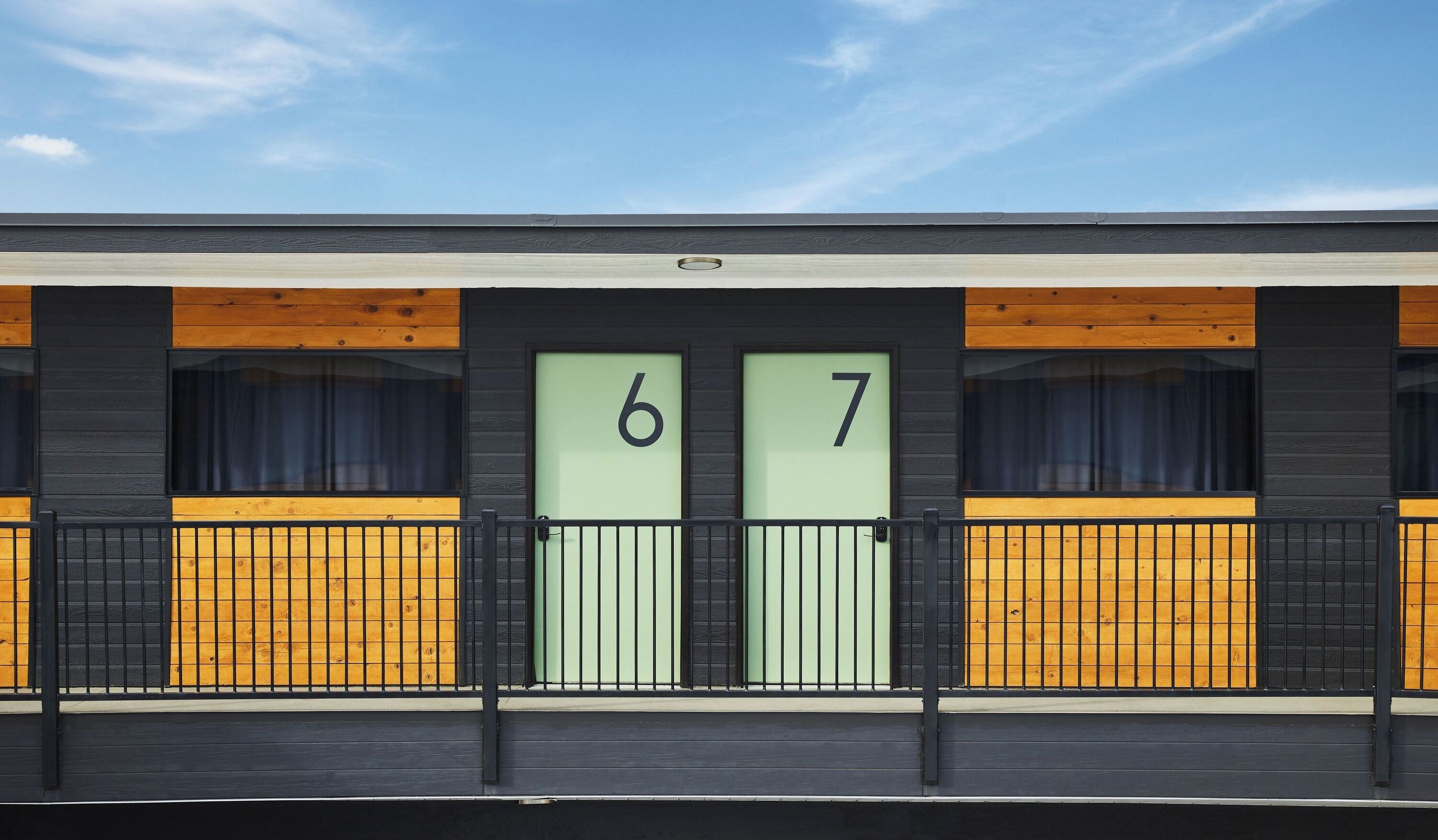 Un edificio con dos puertas, identificadas con los números 6 y 7, cada una con una ventana y un portón de metal negro.