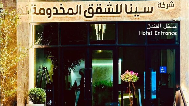 La entrada de un hotel con un letrero en árabe e inglés que indica la entrada del hotel.