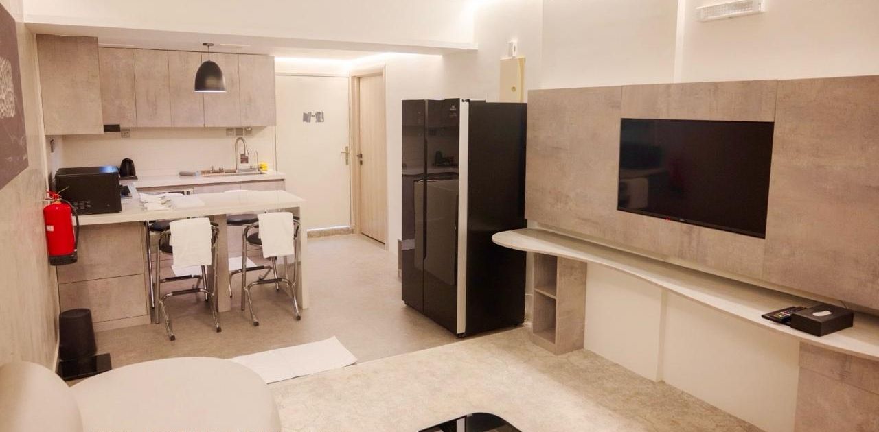 Una cocina moderna con comedor, televisor grande y refrigerador.