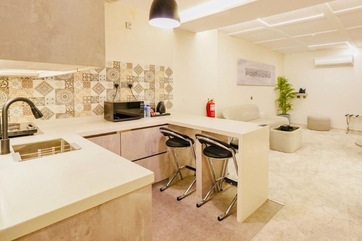A modern executive suite with a kitchen, dining area, and a small bathroom.