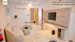 Una sala de estar moderna con un sofá, un reposapiés y un televisor de pantalla plana montado en la pared.
