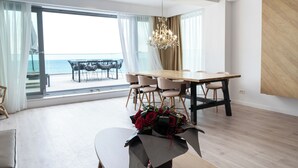 A modern dining area with a view of the sea, a chandelier, and a table with chairs. - Wave 2 Promenada Apartments (Mamaia-Sat)