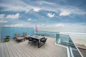 Une terrasse avec une table et des chaises donnant sur l’océan.