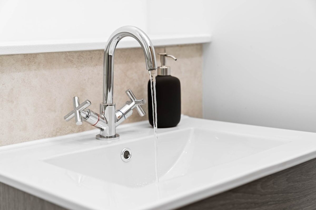 A modern bathroom sink with a chrome faucet and a soap dispenser.