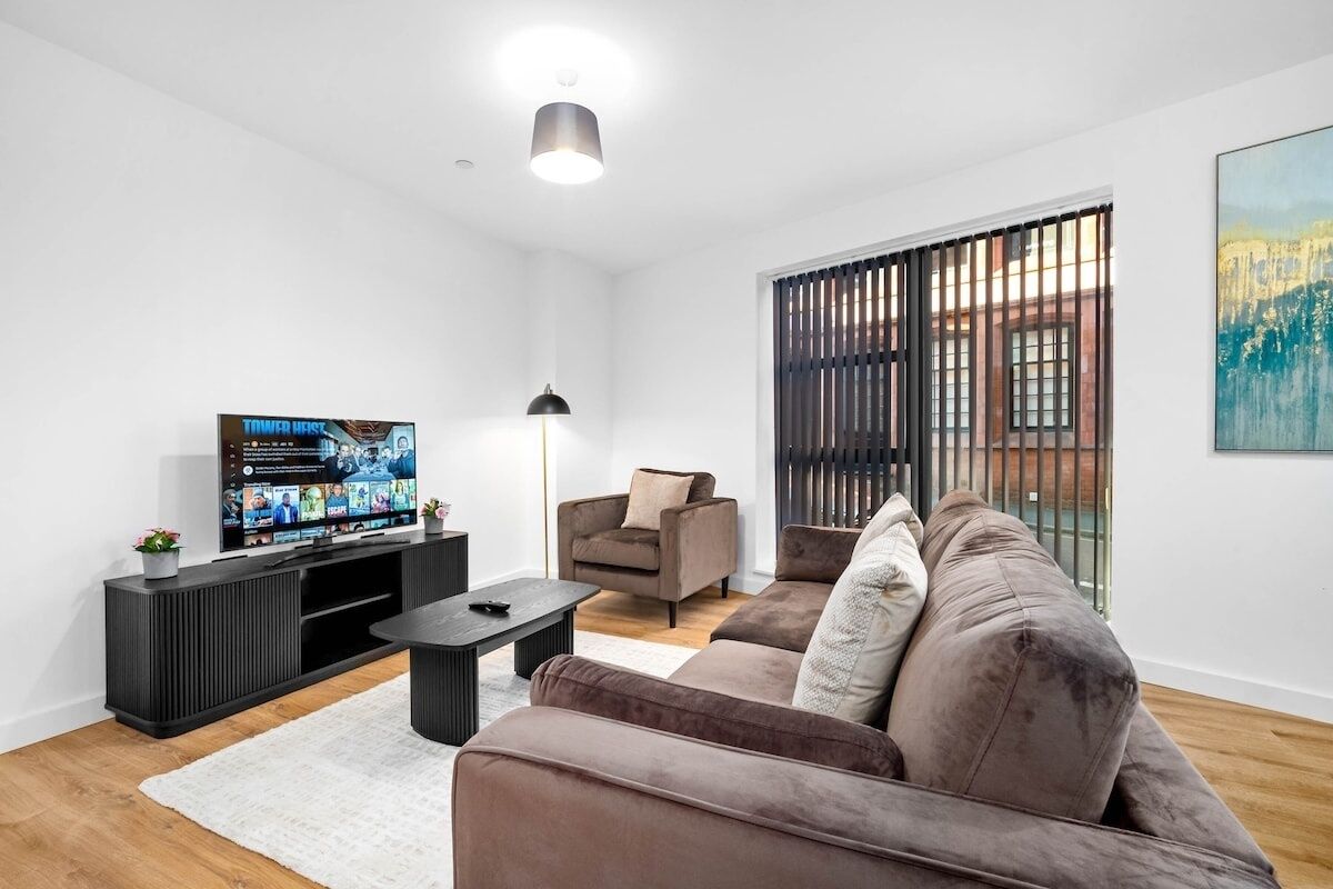 Una sala de estar moderna con un televisor de pantalla plana, un sofá, un sillón y una mesa de centro.
