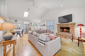 A spacious living area with a fireplace, a sofa, a dining table, and a kitchen in the background. - Experience tranquility at The Red Farmhouse in secluded Fennville, MI, with 4 bedrooms. (Fennville)