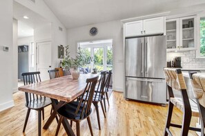 A modern kitchen with a stainless steel refrigerator, wooden dining table, and chairs. - Experience tranquility at The Red Farmhouse in secluded Fennville, MI, with 4 bedrooms. (Fennville)