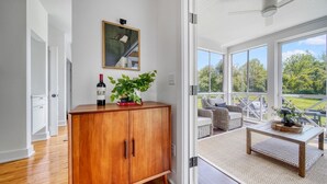 Un intérieur moderne avec un meuble en bois, un miroir et une vue sur une terrasse aménagée avec du mobilier d’extérieur.