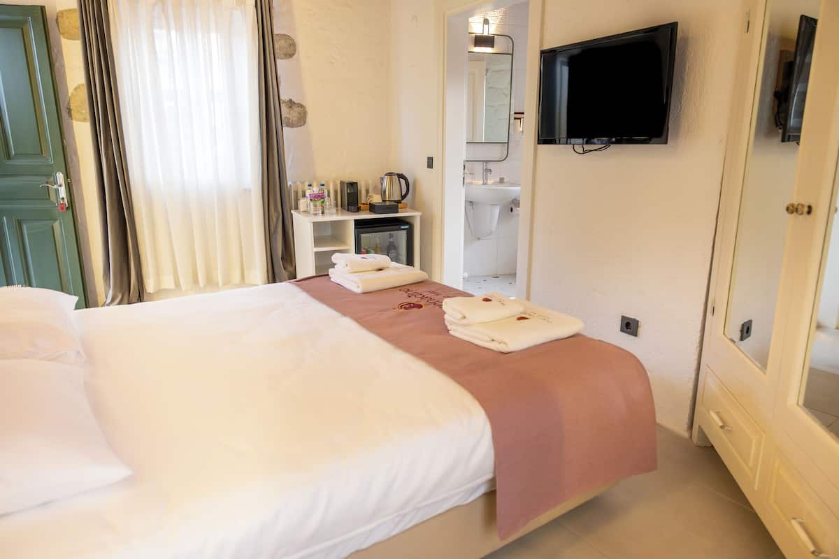 Ein Hotelzimmer mit Bett, Wandfernseher, Waschbecken und Spiegel.