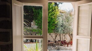 An open door to a room with a view of an outdoor swimming pool, wicker furniture, and a stone wall. - La Grenadine Hotel (Cesme)