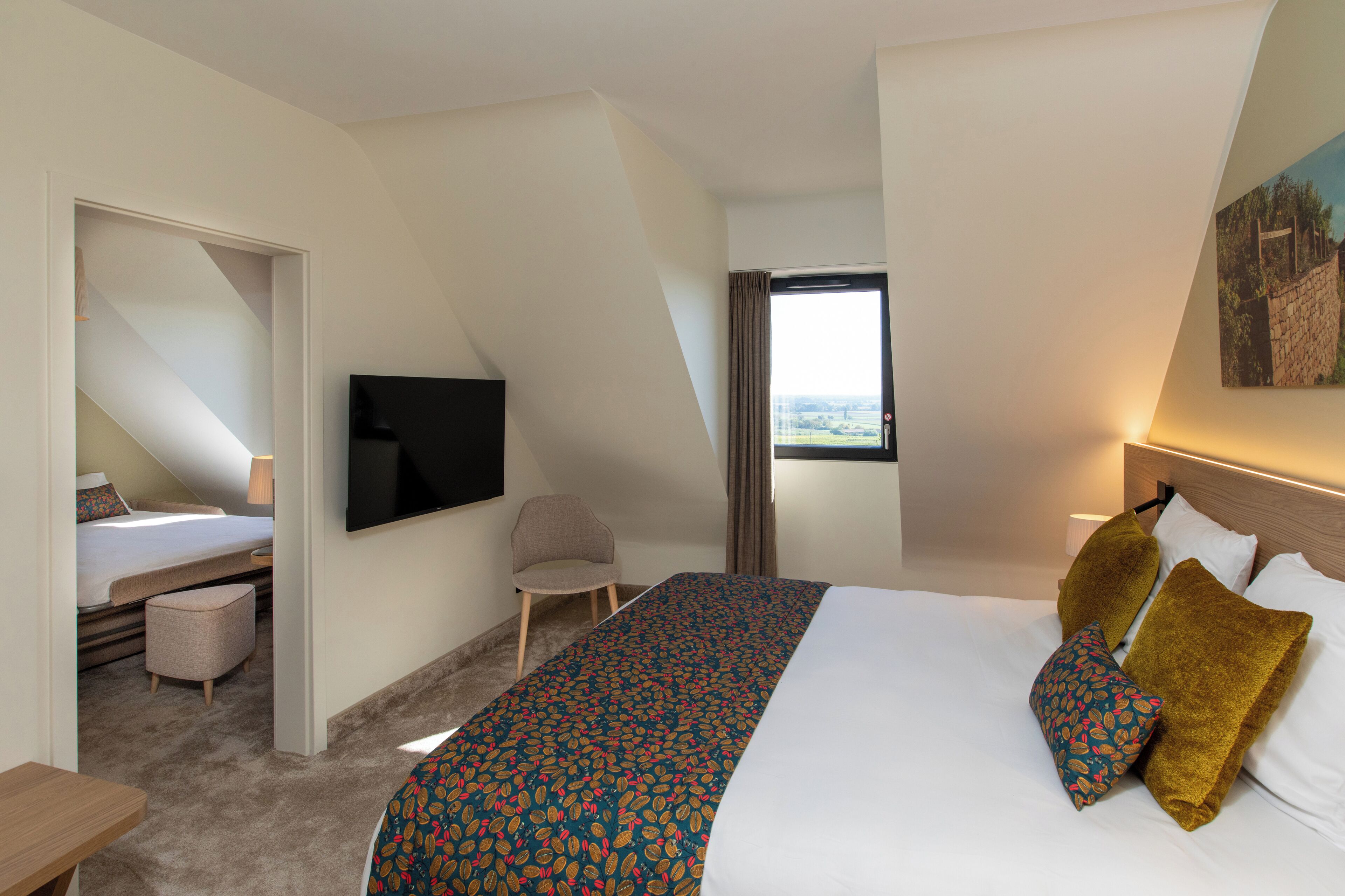 A hotel room with a large bed, a television, a chair, and a window with a view.