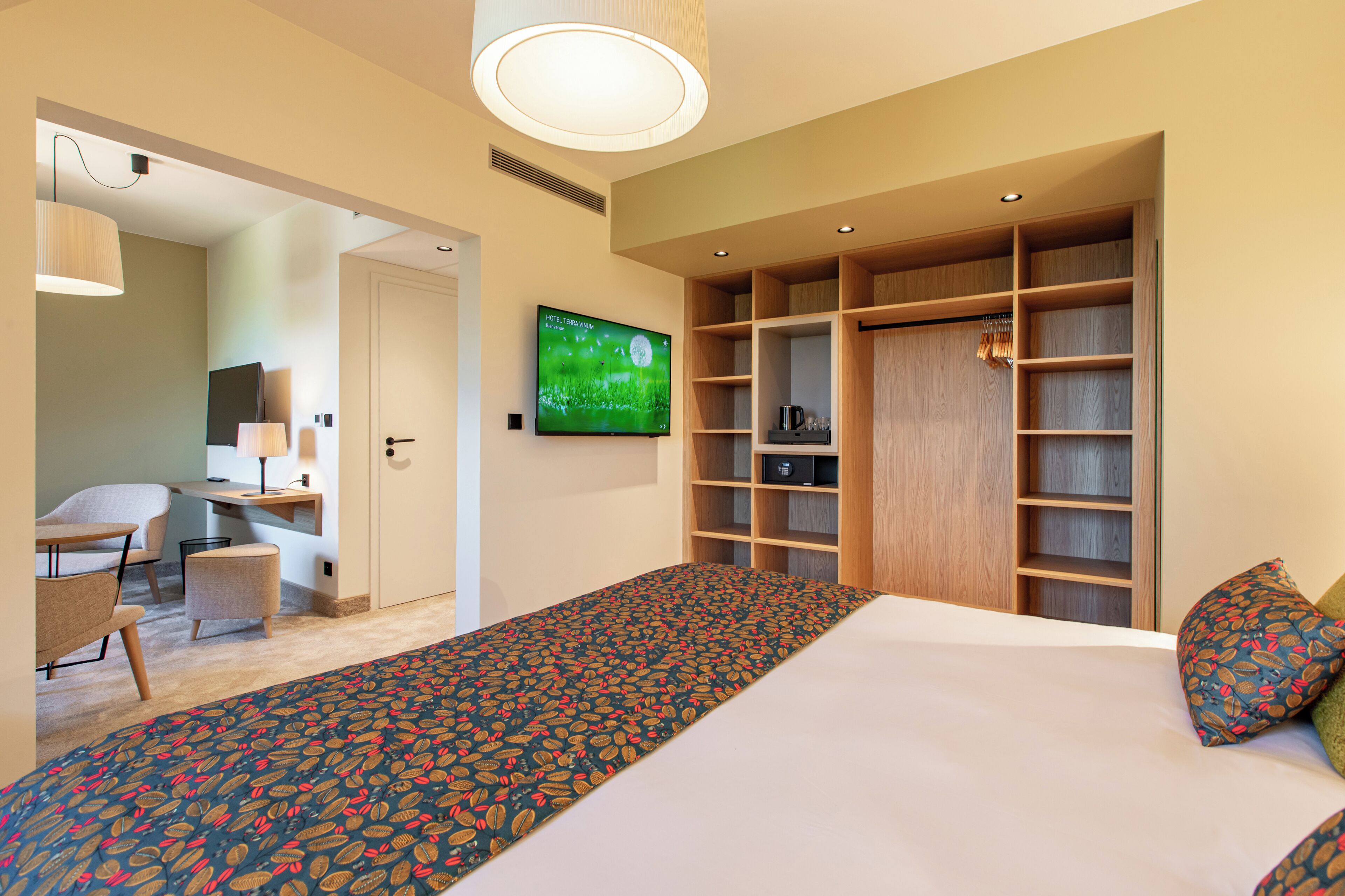 A hotel room with a bed, a TV, a desk with a chair, and a walk-in closet.