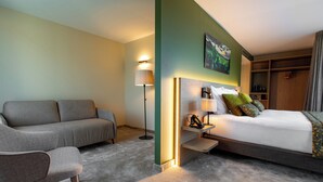 Una camera d'albergo con un letto, un divano, una lampada e un quadro appeso al muro.