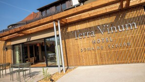 Esterno dell'Hotel Terra Vinum con facciata in legno, ampie vetrate e area salotto all'aperto.