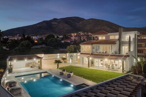 A modern house with a swimming pool, outdoor seating, and a view of a mountain. - LaGon Luxury Villa (Kalyvia Thorikou)