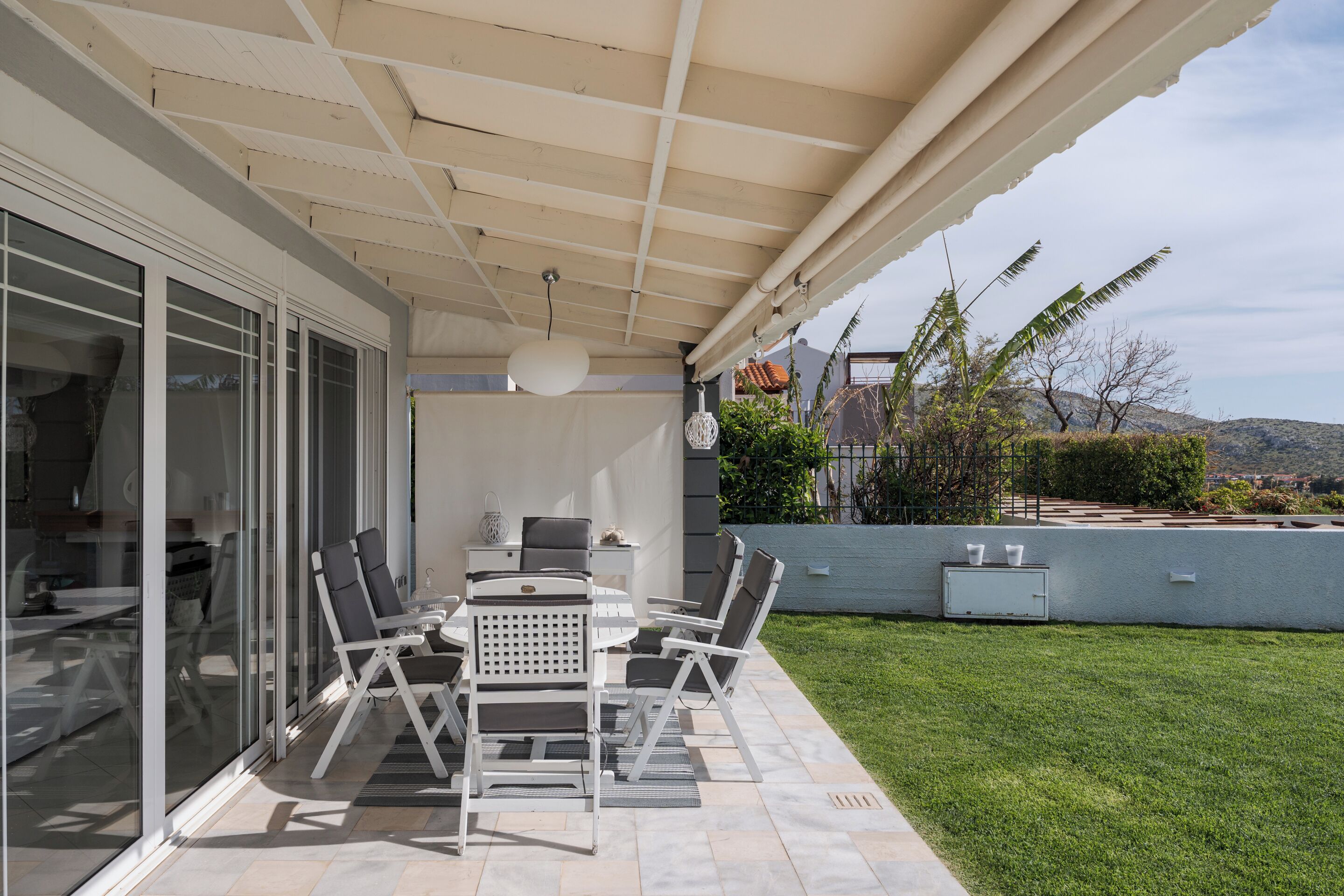 A patio with a table and chairs, a ceiling fan, and a view of the backyard.