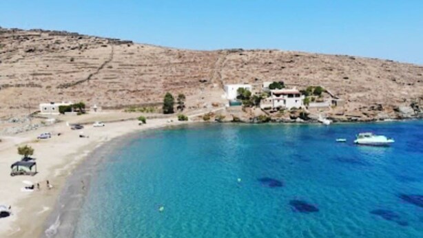 A coastal area with clear blue waters, a sandy beach, and buildings on a hillside. - Simousi Studio 1 sea View on the Beach (Kithnos)