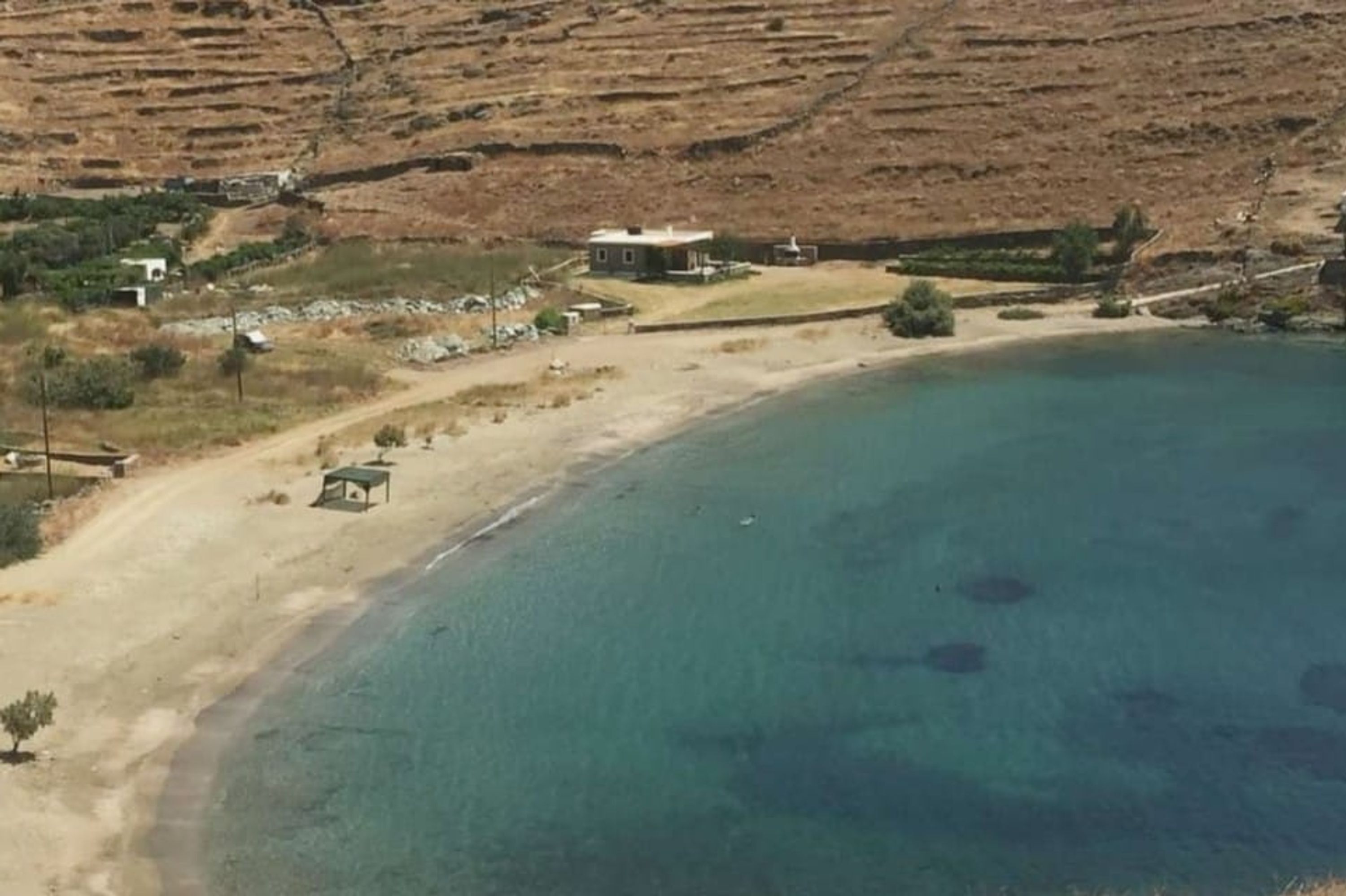 A coastal area with terraced fields, a small building, and a sandy beach.
