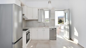 Een moderne keuken met witte kasten, een roestvrijstalen koelkast, een vaatwasser en een raam met gordijnen.