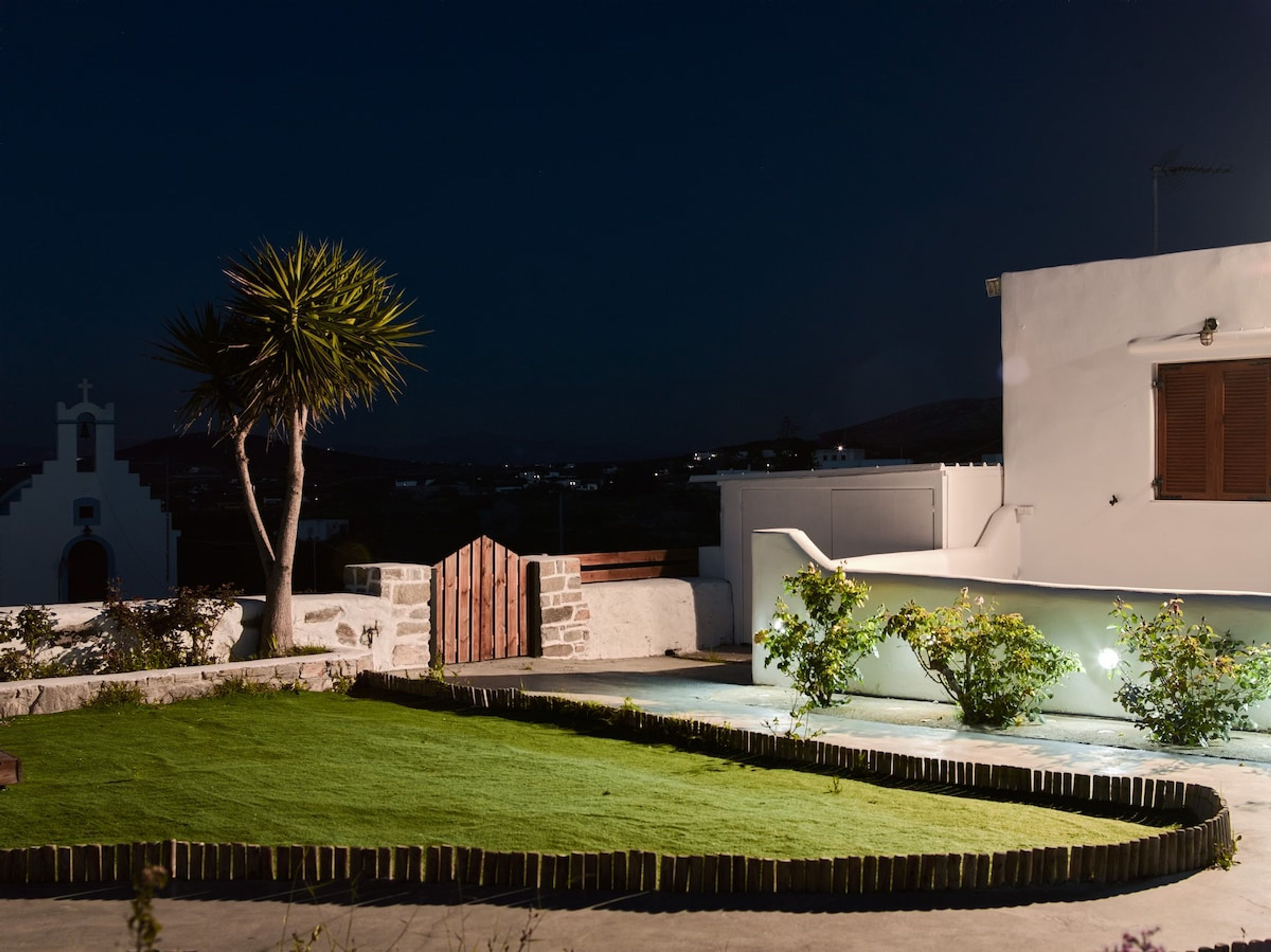 A modern building with a white facade, a stone wall, and a well-maintained lawn.